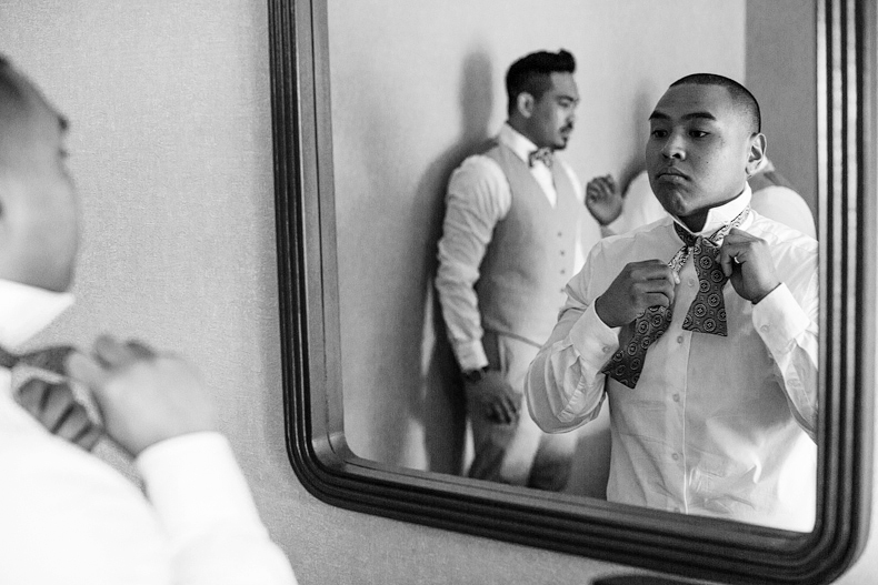 Groom tying bowtie at vineyard wedding