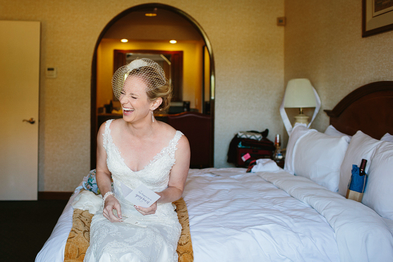 This is a cute candid photo of the bride laughing while reading the card from her groom to be.