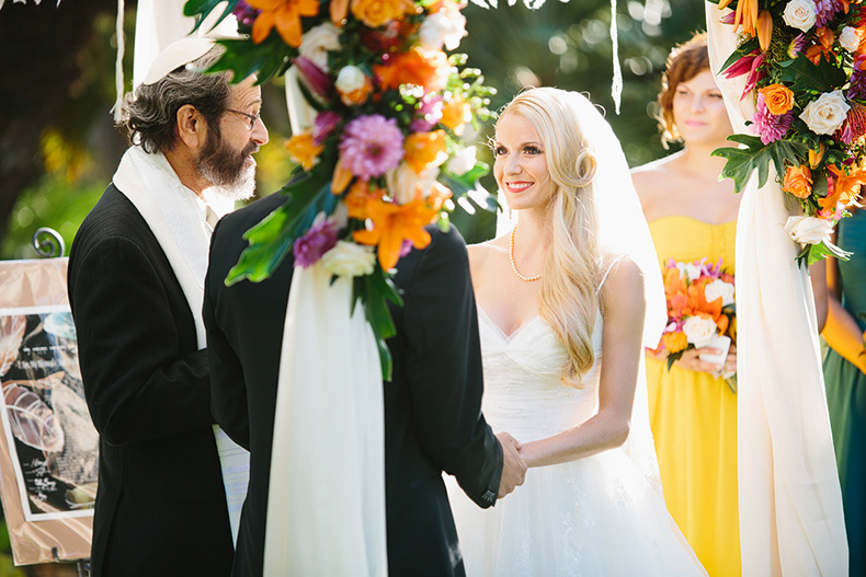 This is a photo of the bride framed in the flowers of her colorful chuppah.