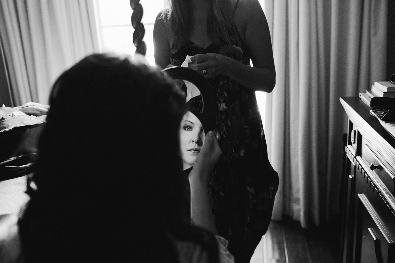 A black and white photo of the bride looking in the mirror. 