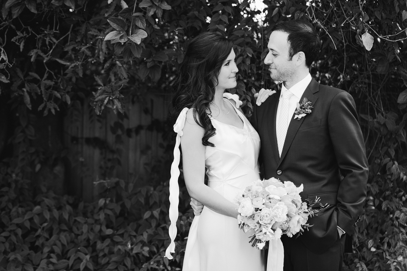 A black and white photo of the couple near trees. 