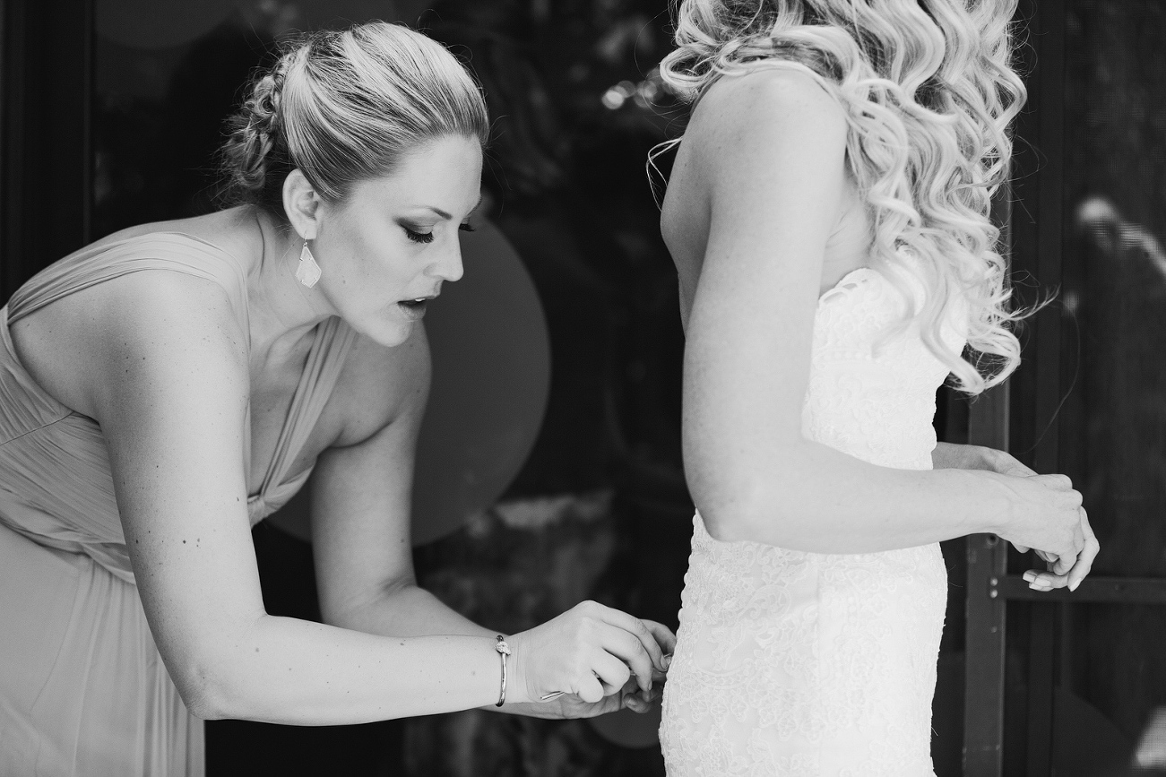 Here is a photo of a bridesmaid helping Sidney button her dress. 