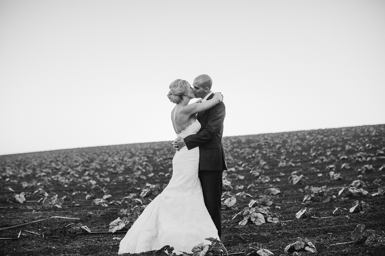 The bride and groom kissing in the fields behind Maravilla Gardens. 