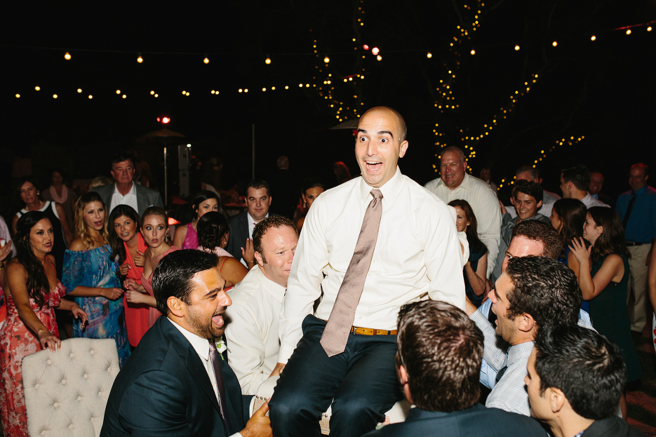 The guests lifted the groom on a chair. 
