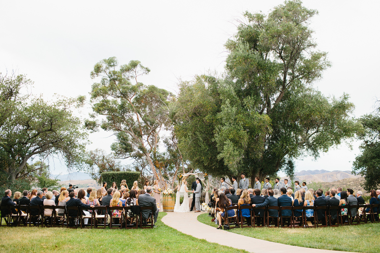 The ceremony was in front of large trees outside. 