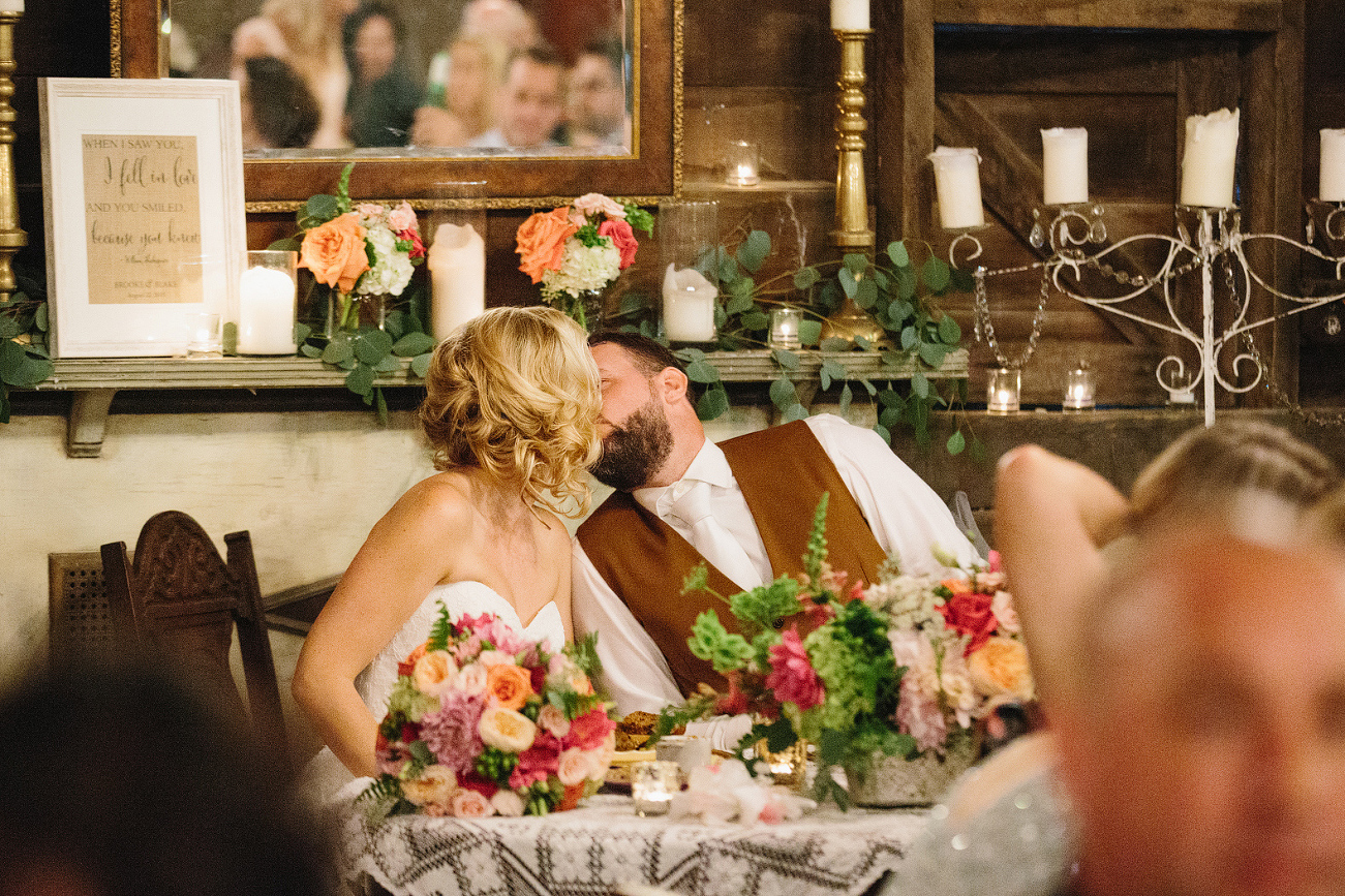 The bride and groom snuck a kiss during dinner. 
