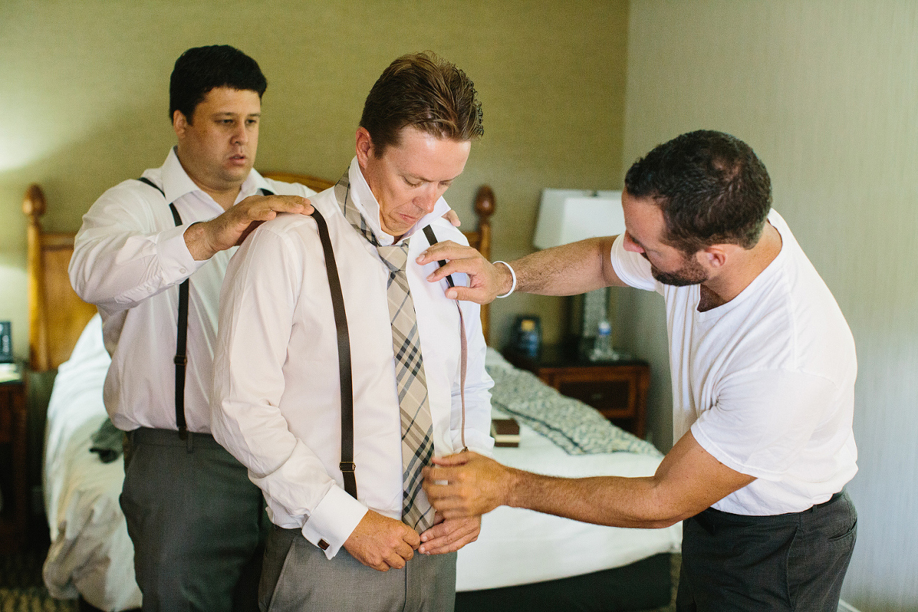 The groomsmen helping Chris put on his tie. 