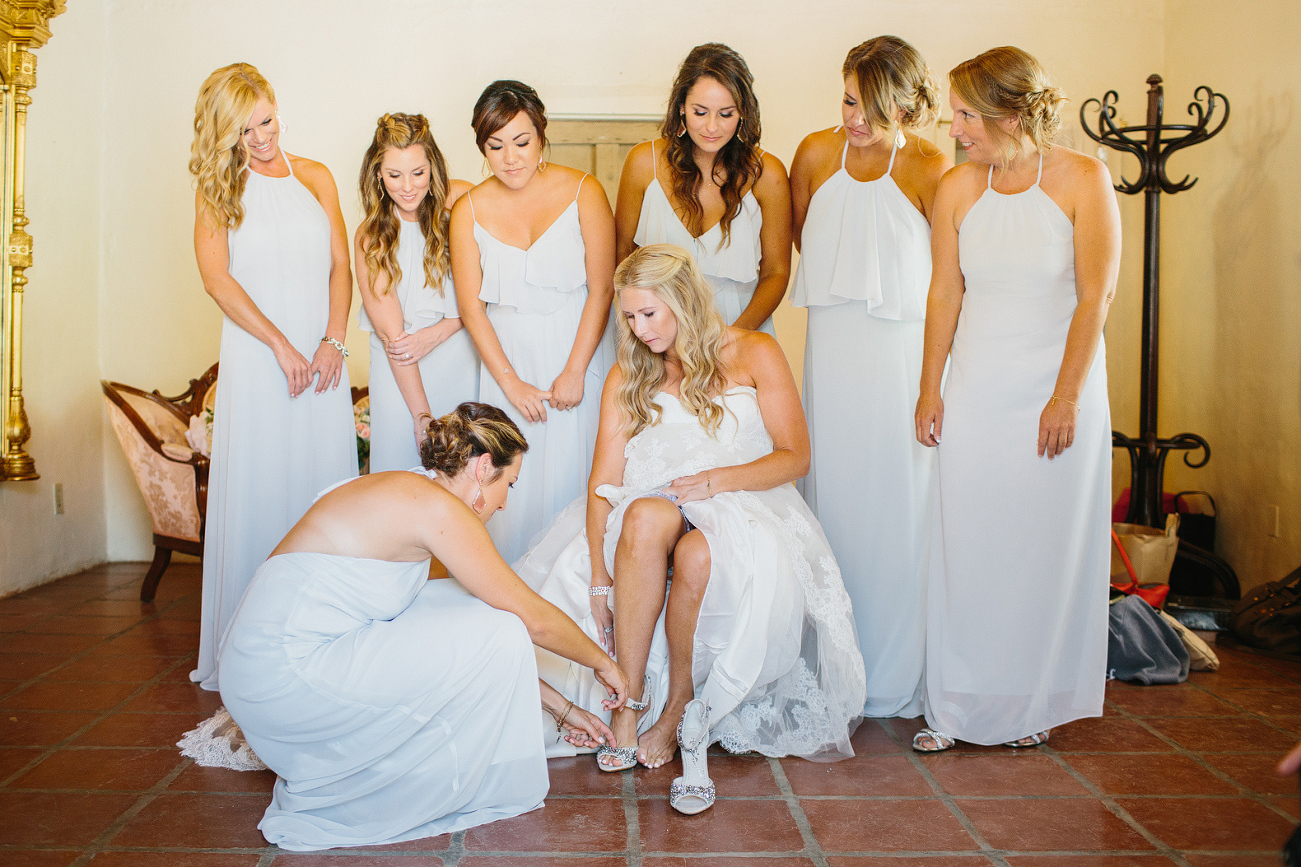 The bridemaids helped Liz put on her shoes. 