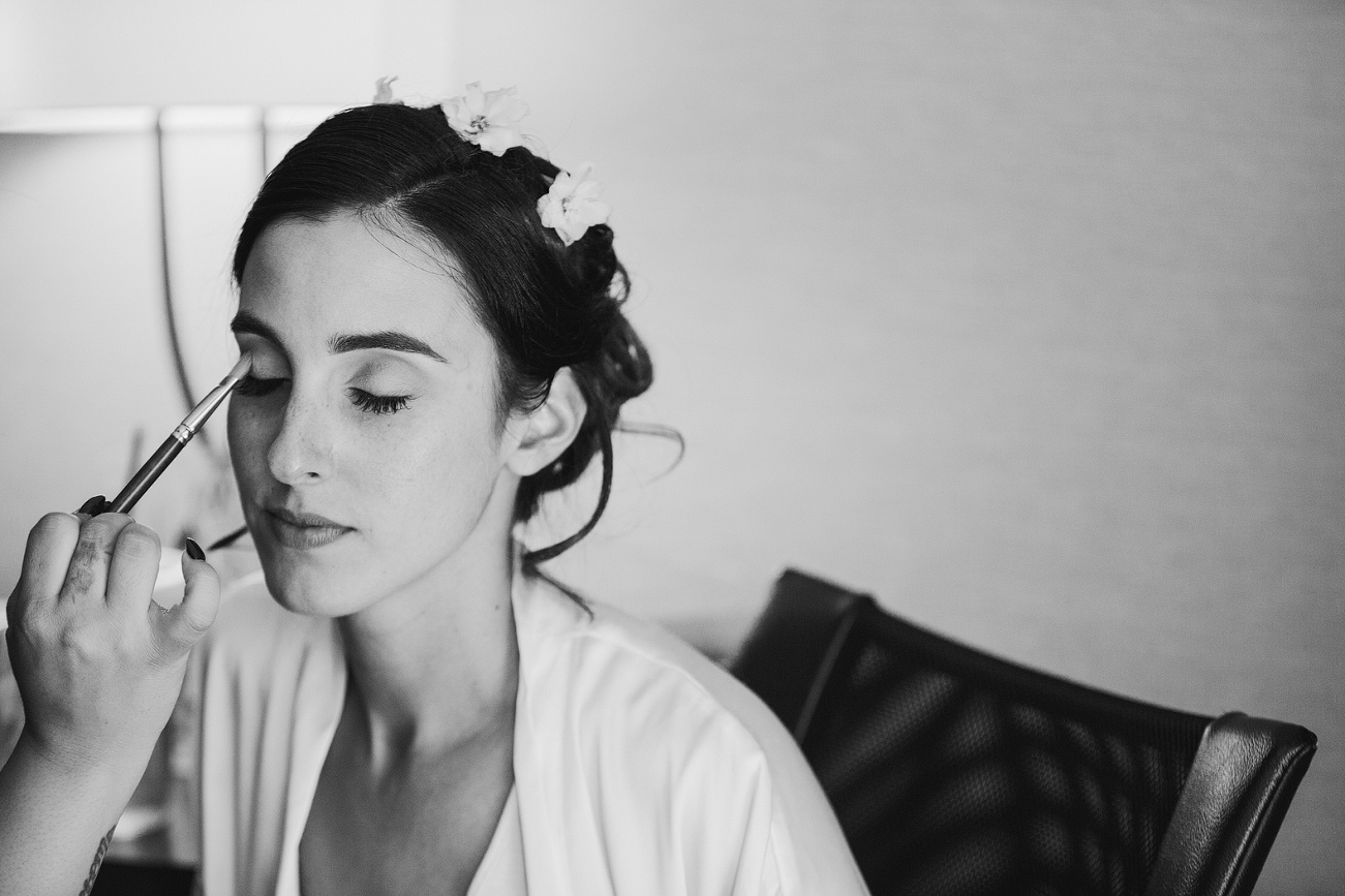 A black and white photo of the bride getting her make up done. 