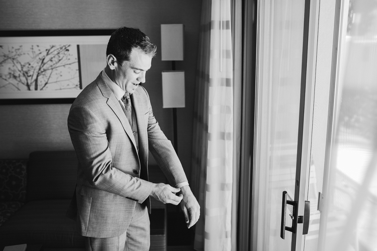 A black and white photo of the groom getting dressed. 