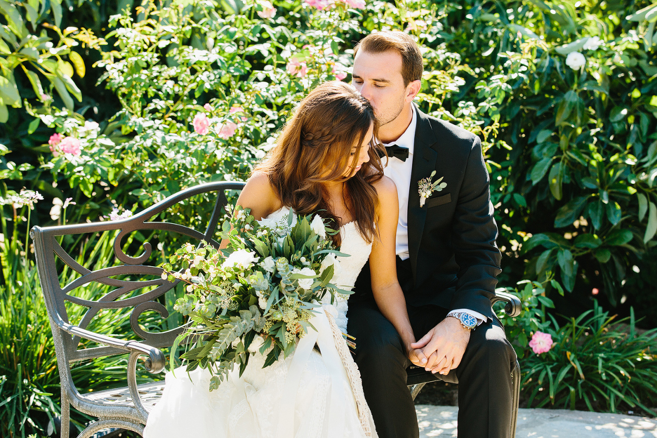 The bride and groom sitting on a bench. 