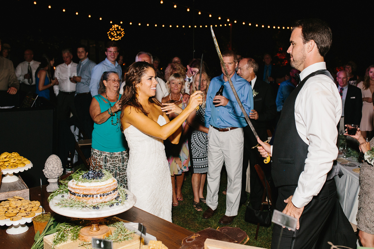 Larissa and Andy cut the cake with special family swords. 