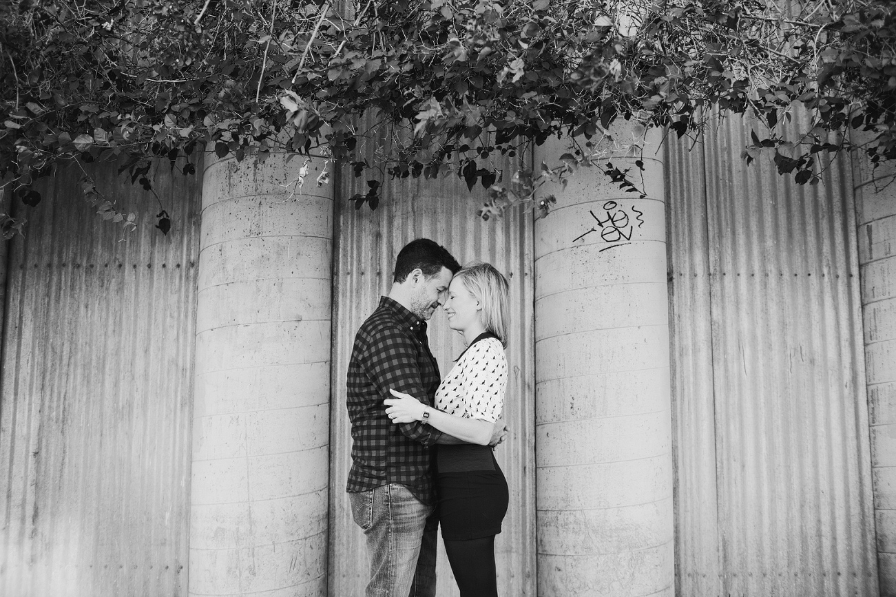 A black and white photo of the couple under greenery. 