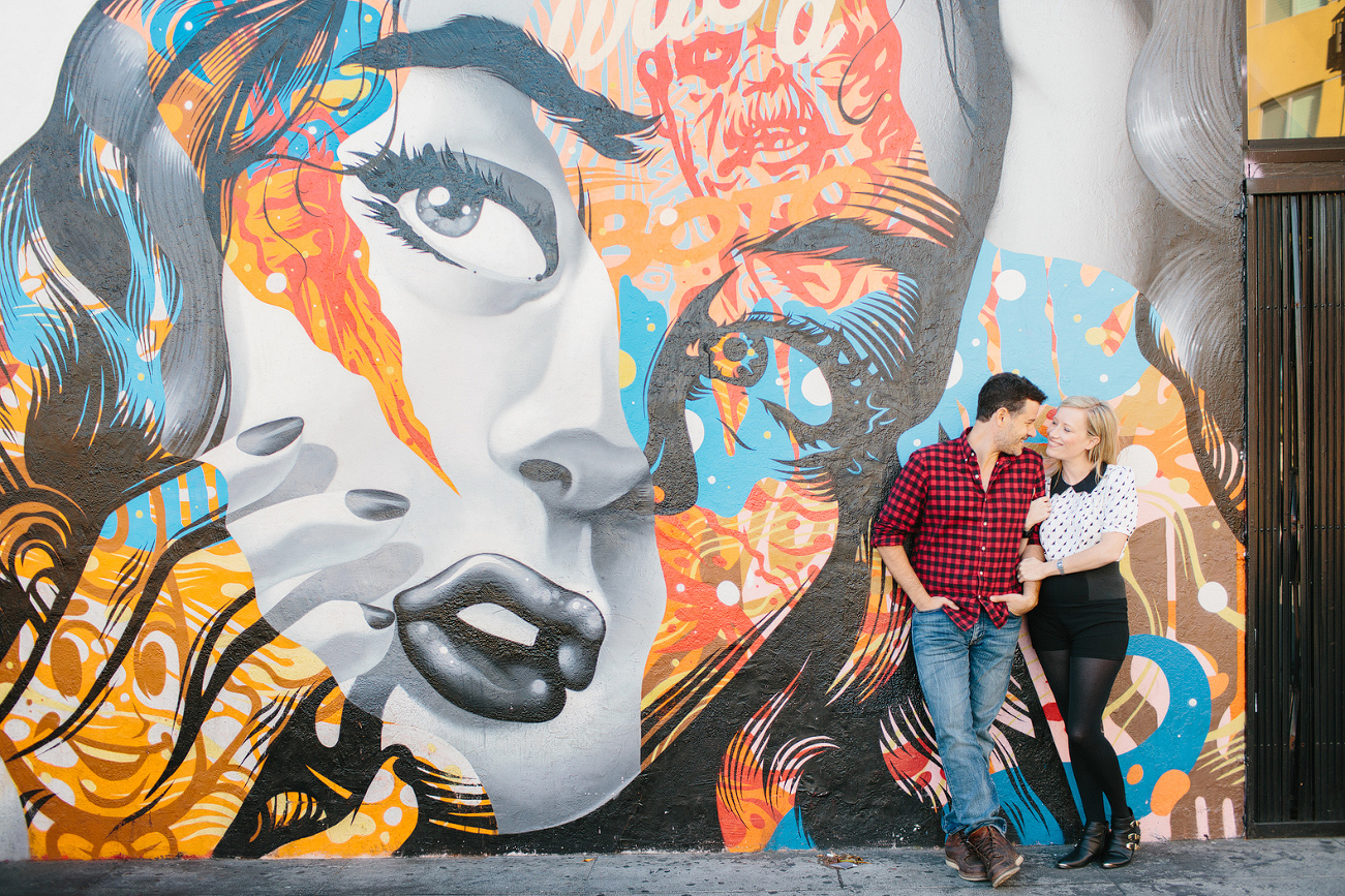 The couple in front of a graffiti wall. 