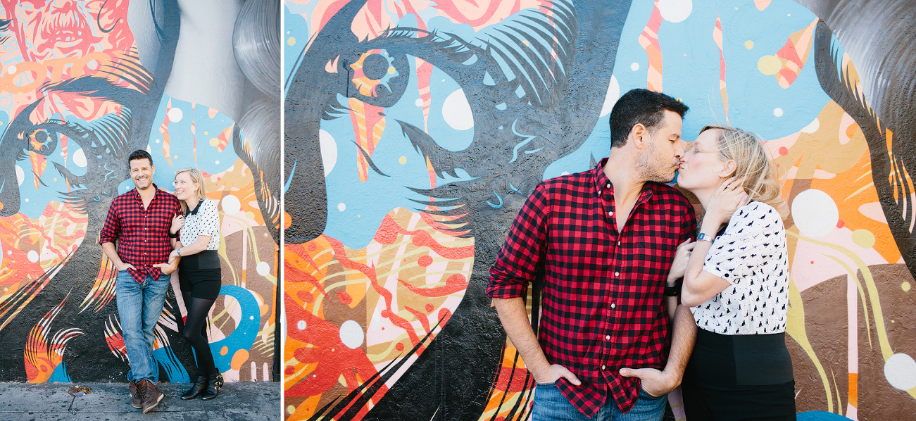 Hayley and David standing by a bright painted wall. 