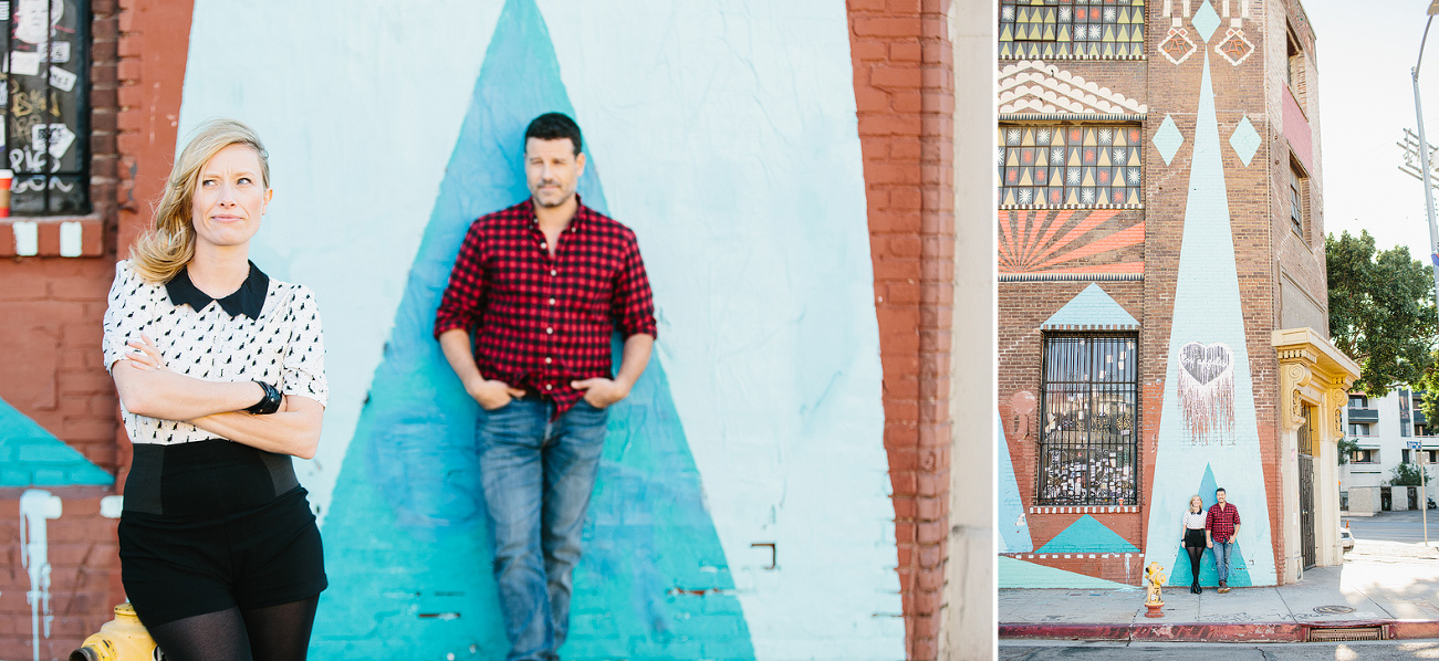 The couple in front of a blue triangle on a brick wall. 