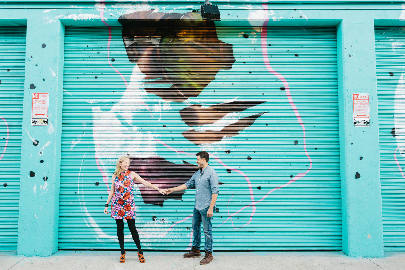 Hayley and David dancing in front of a teal mural. 