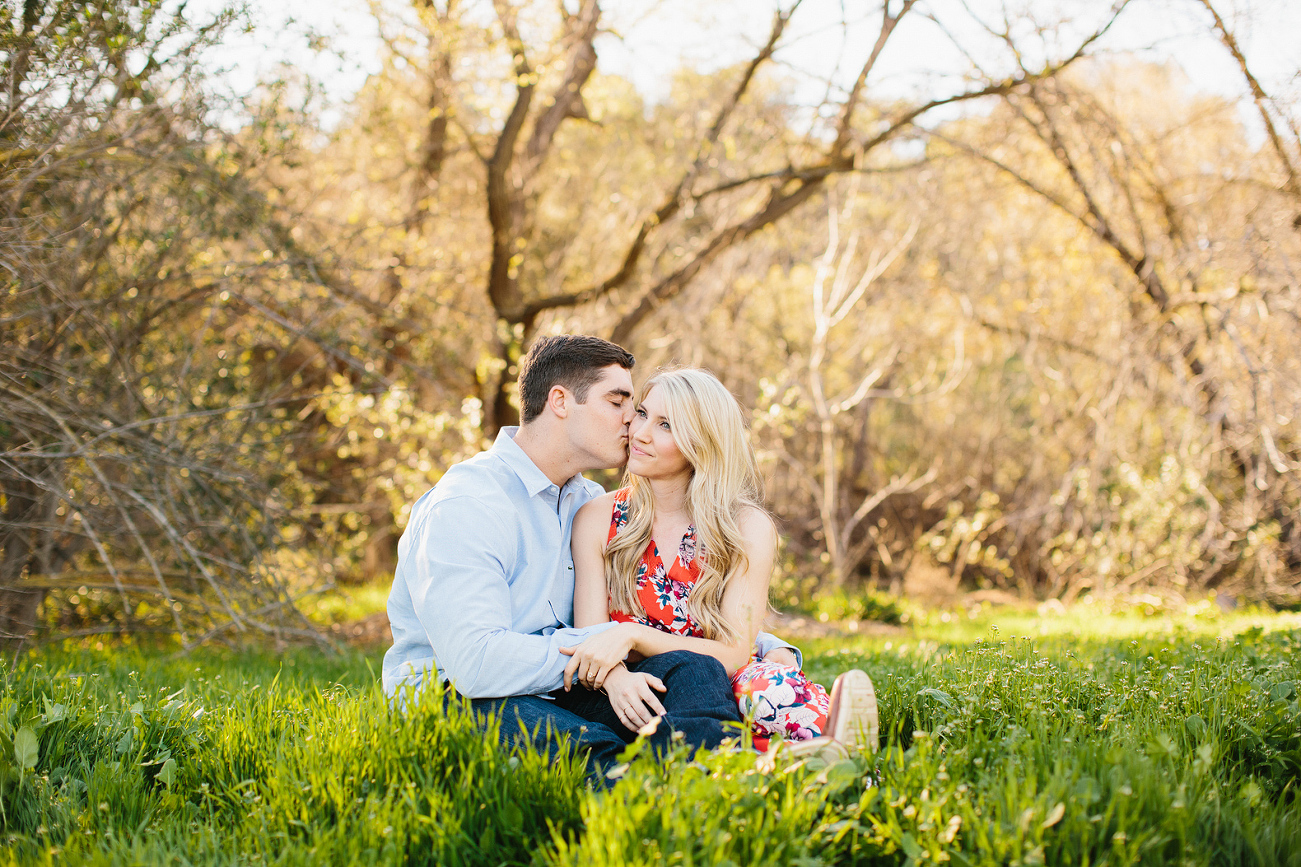 The couple sitting on the grass at the park. 