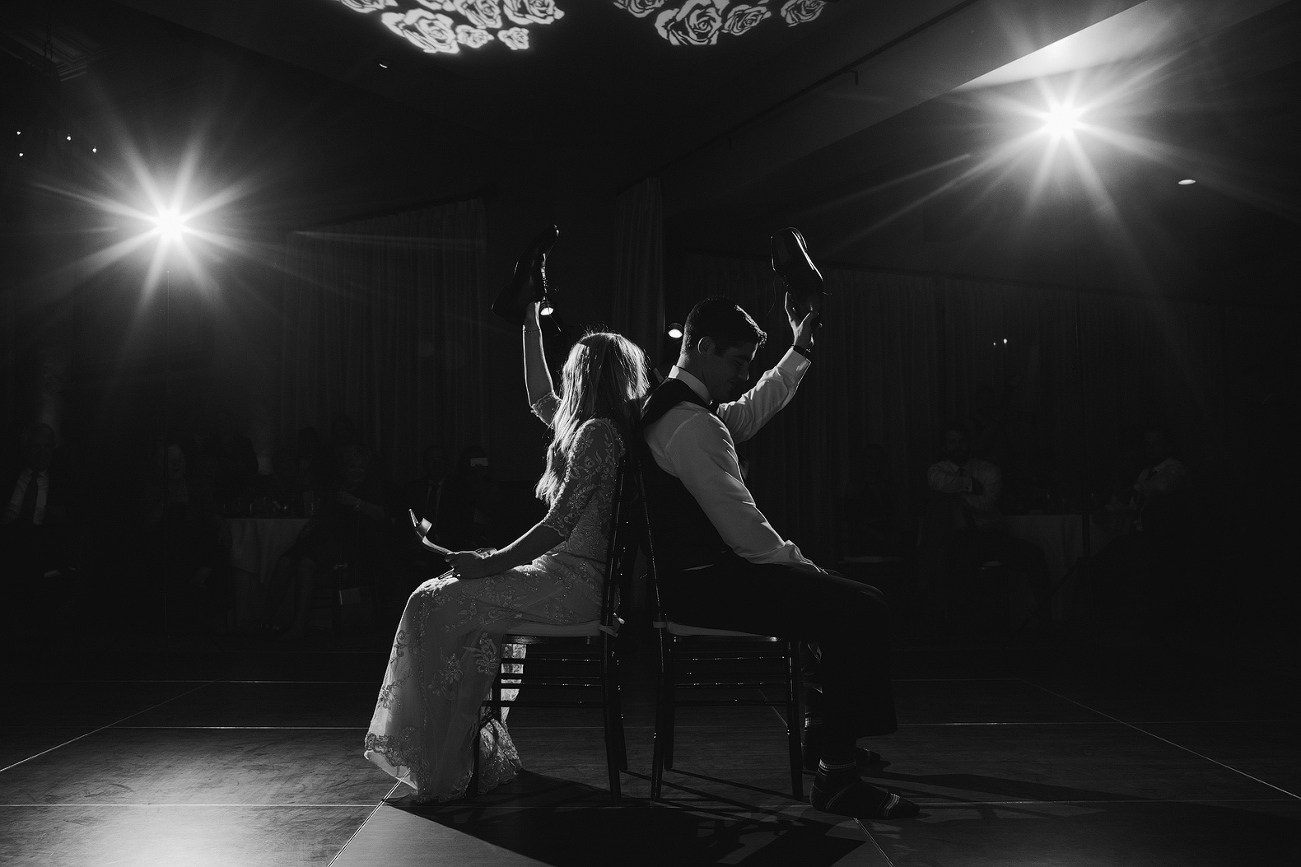 A cool black and white photo of the bride and groom lifting their shoes. 