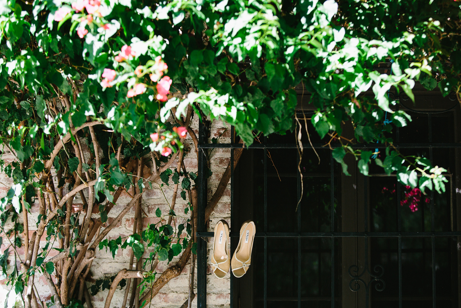 The bride's shoes hanging on a gate. 