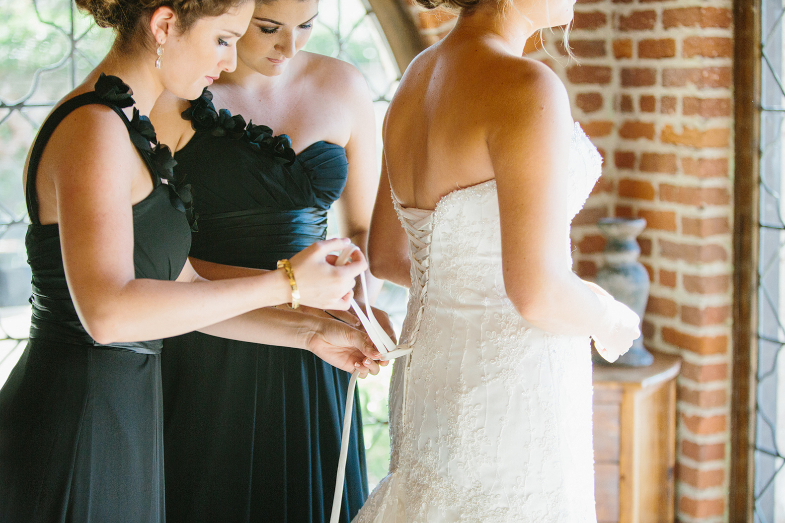The bridesmaids helping lace Morgan's dress. 