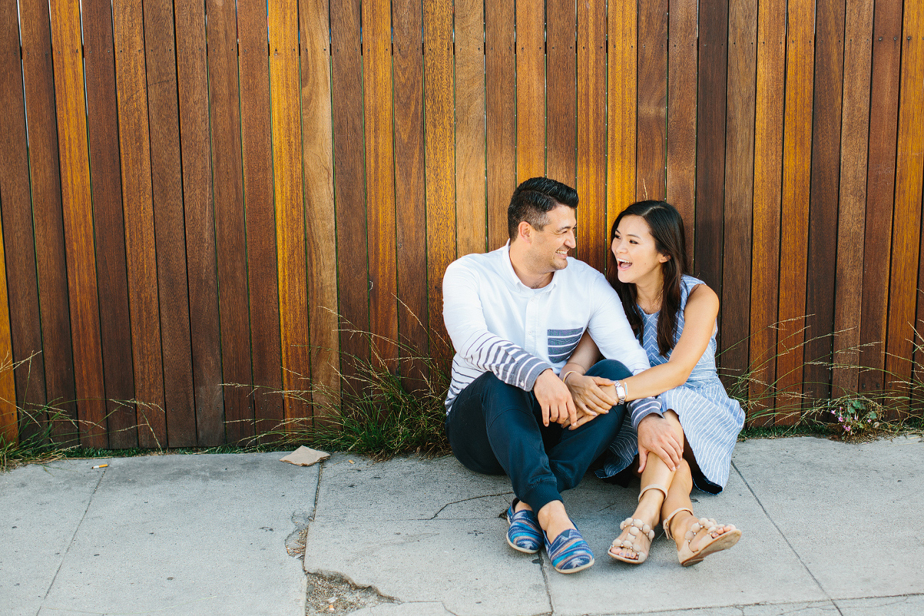 The couple in front of a wood fence. 