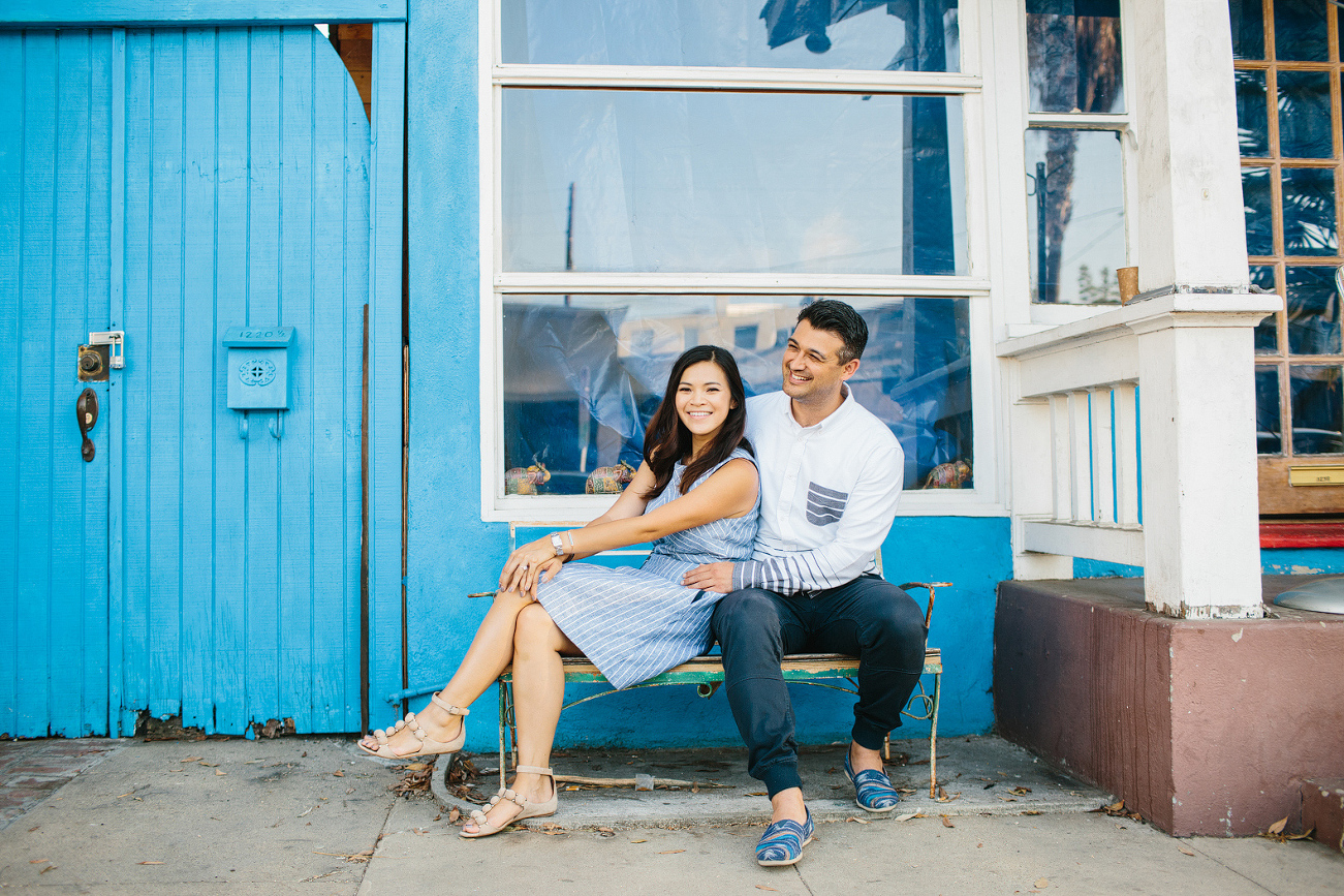 The couple in front of a blue building. 