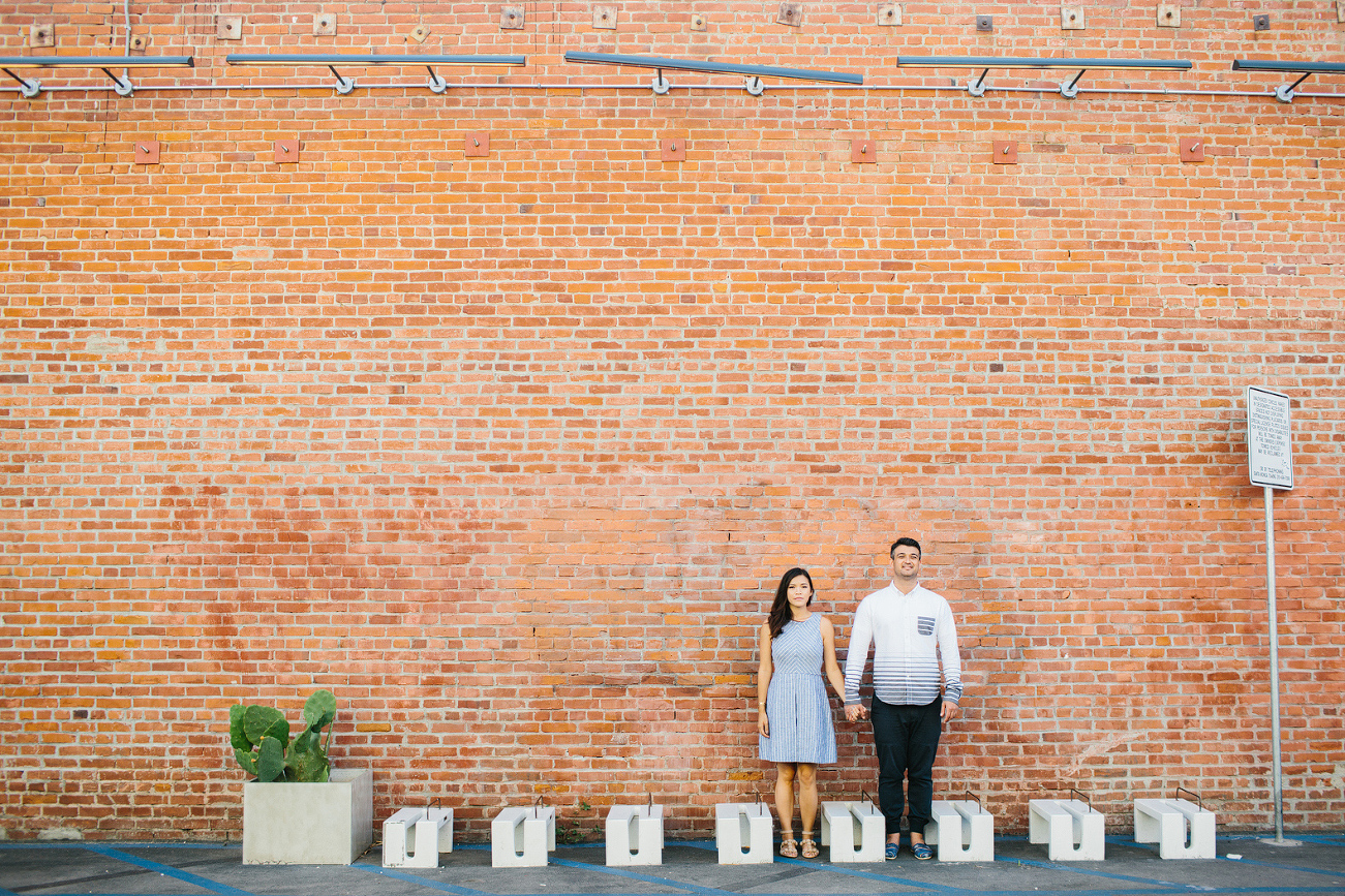 The couple by a brick building. 