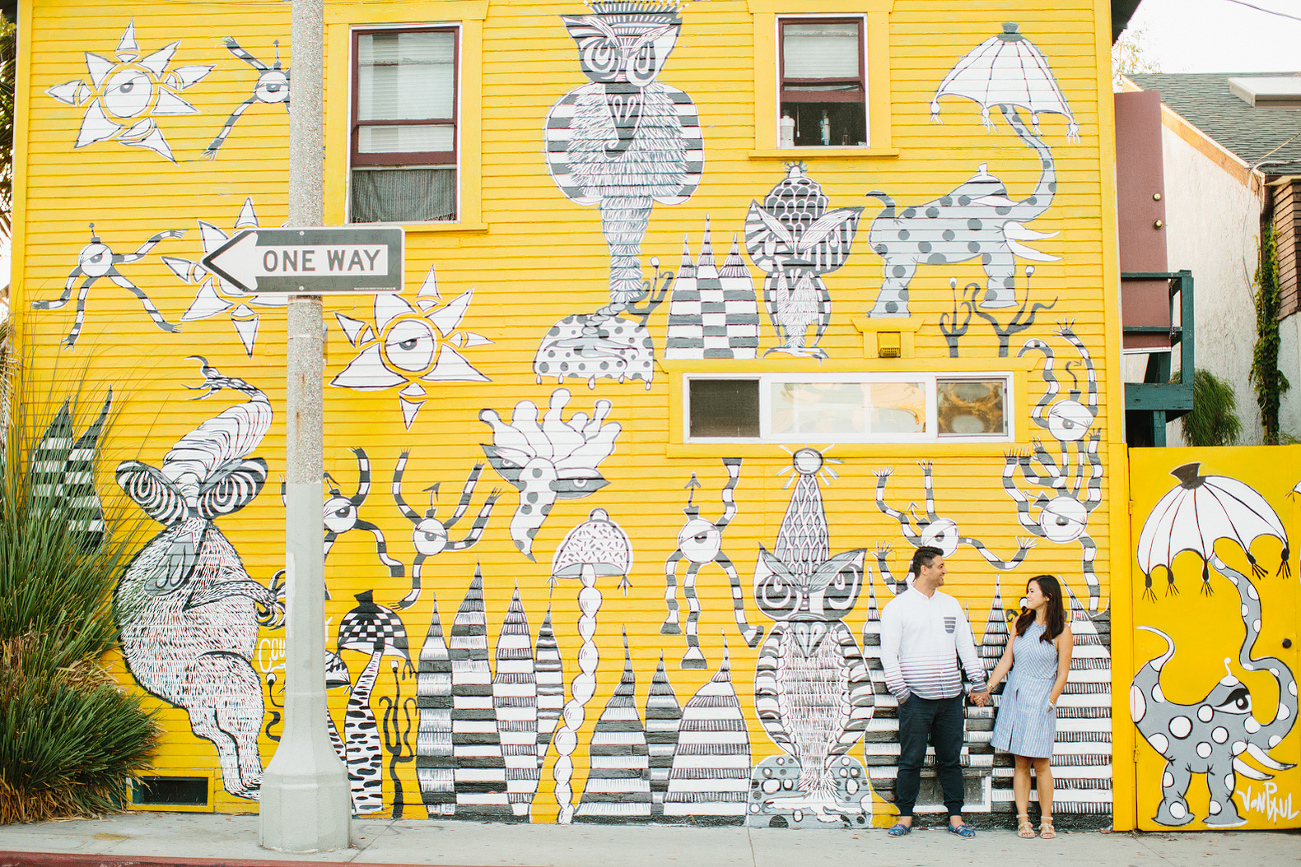 The couple in front of a bright silly wall. 