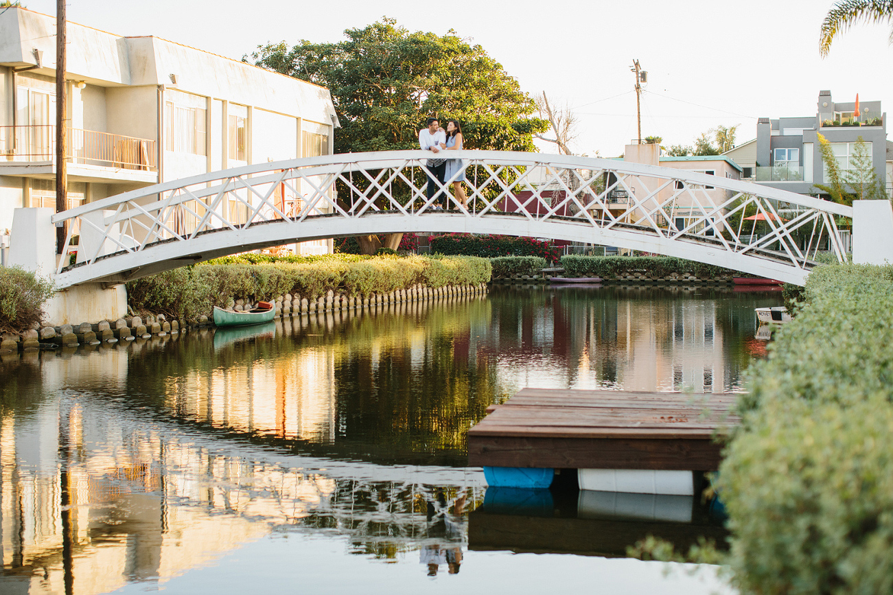 The couple standing on a bridge. 