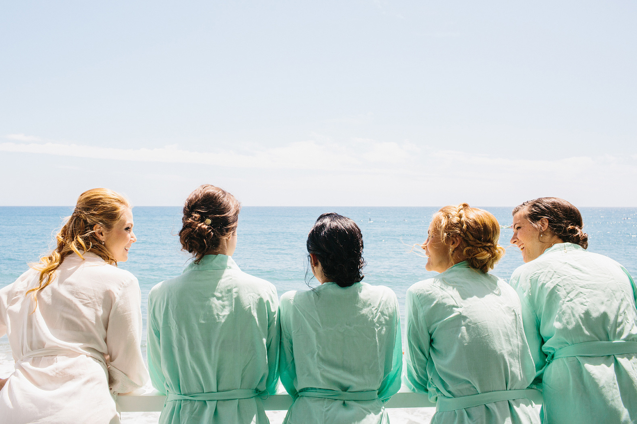 The bride and bridesmaids looking out over the ocean. 