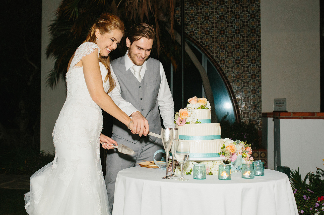 The bride and groom cutting the cake together. 