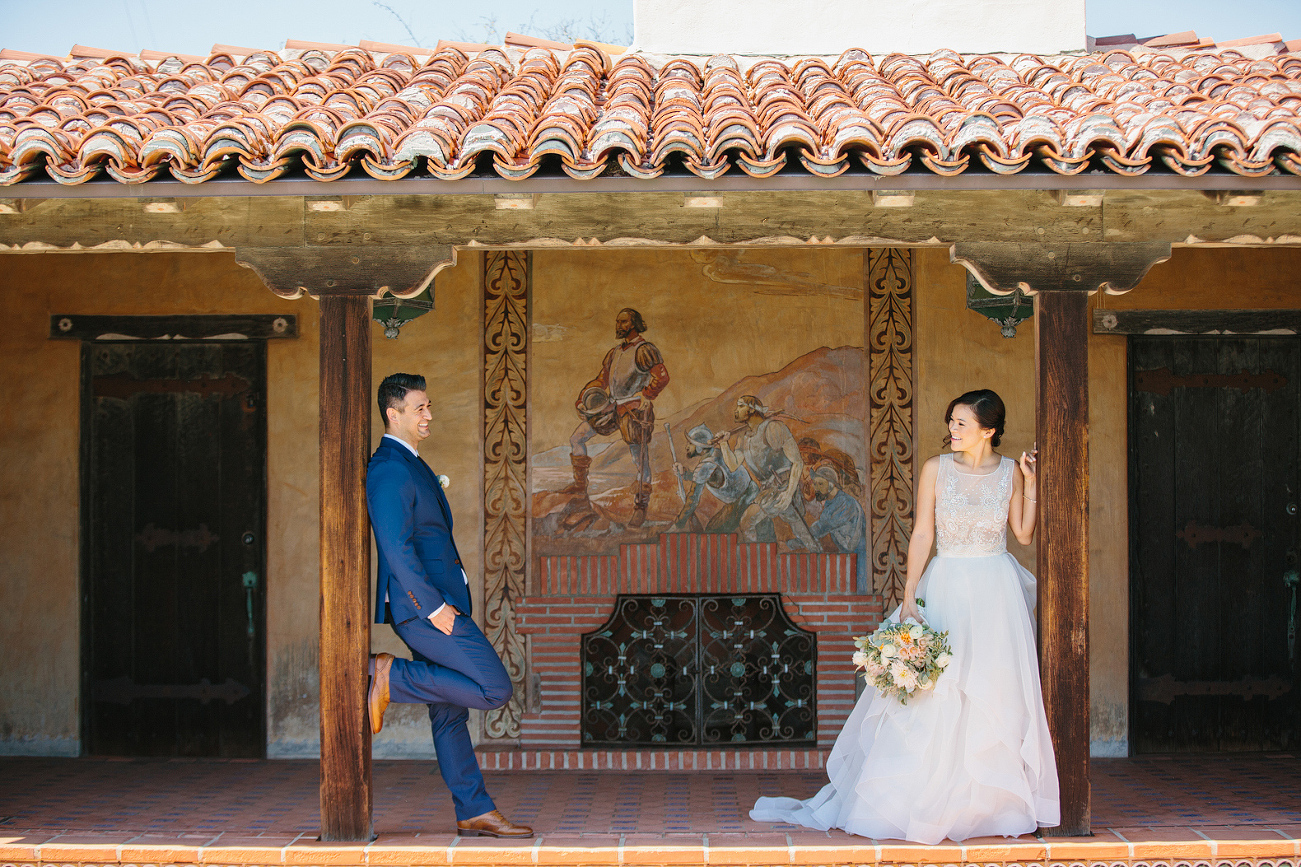 The bride and groom leaning on wood posts. 