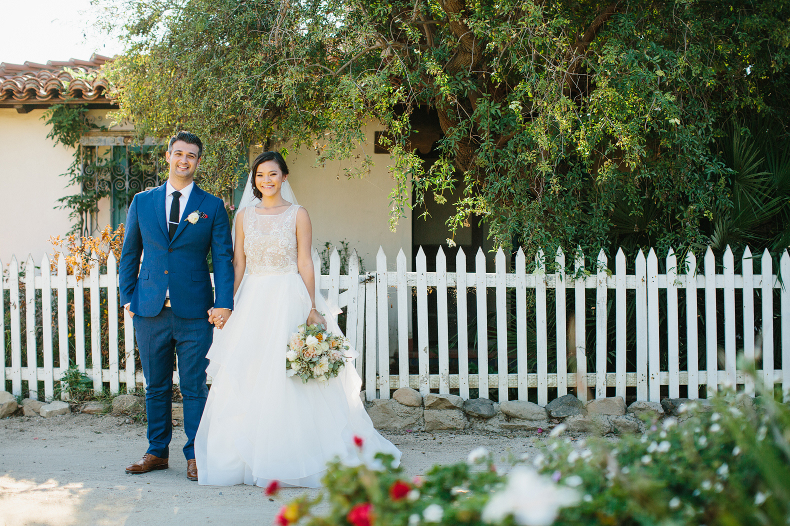 The couple in front of a picket fence. 