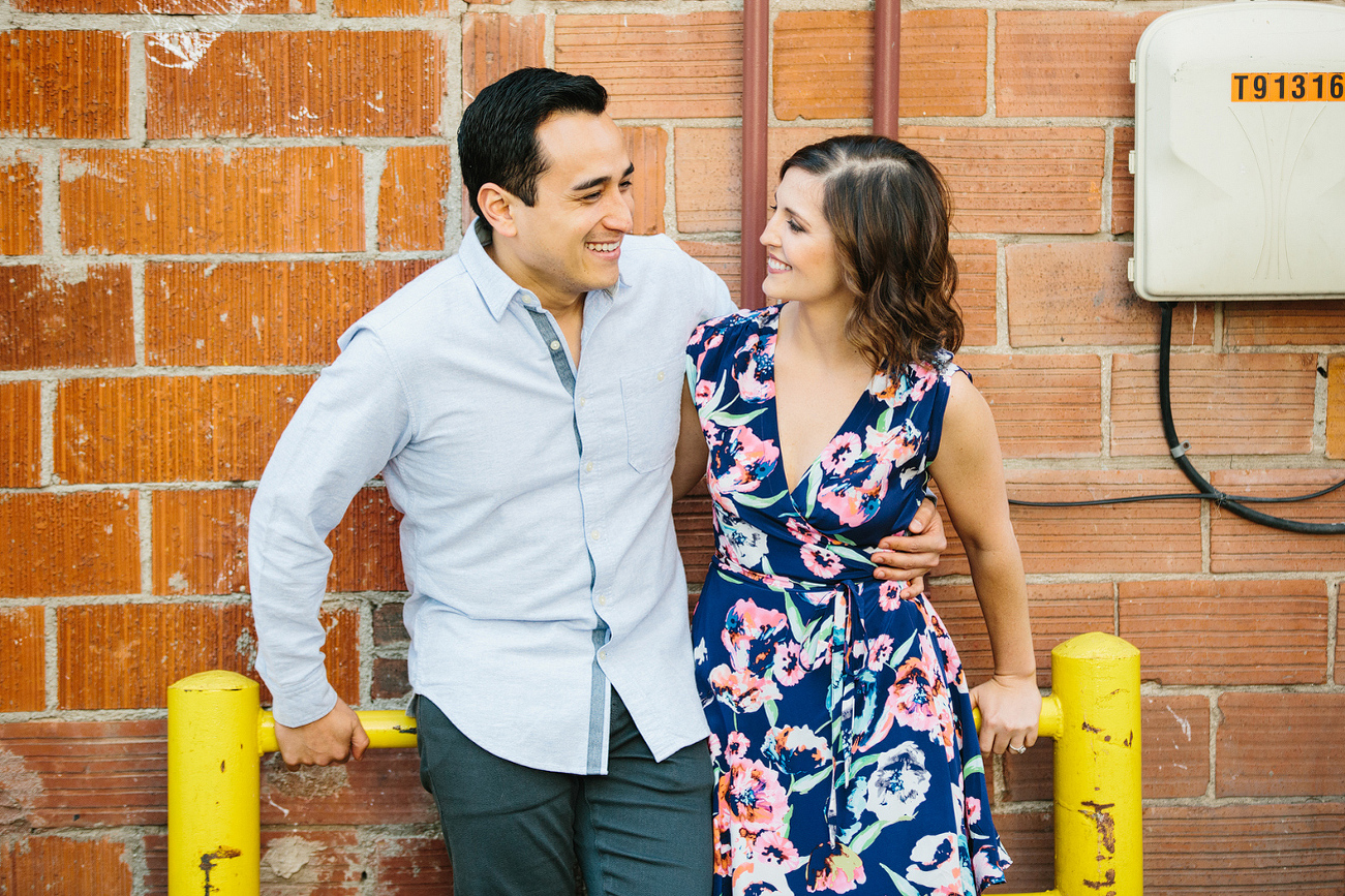 The couple leaning on a brick building. 