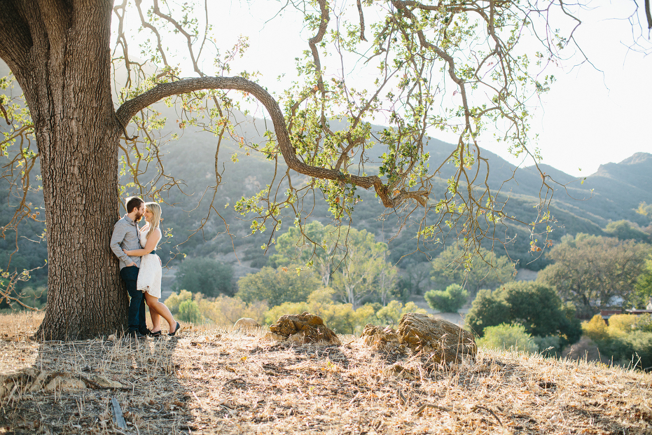 The couple leaning on a tree. 