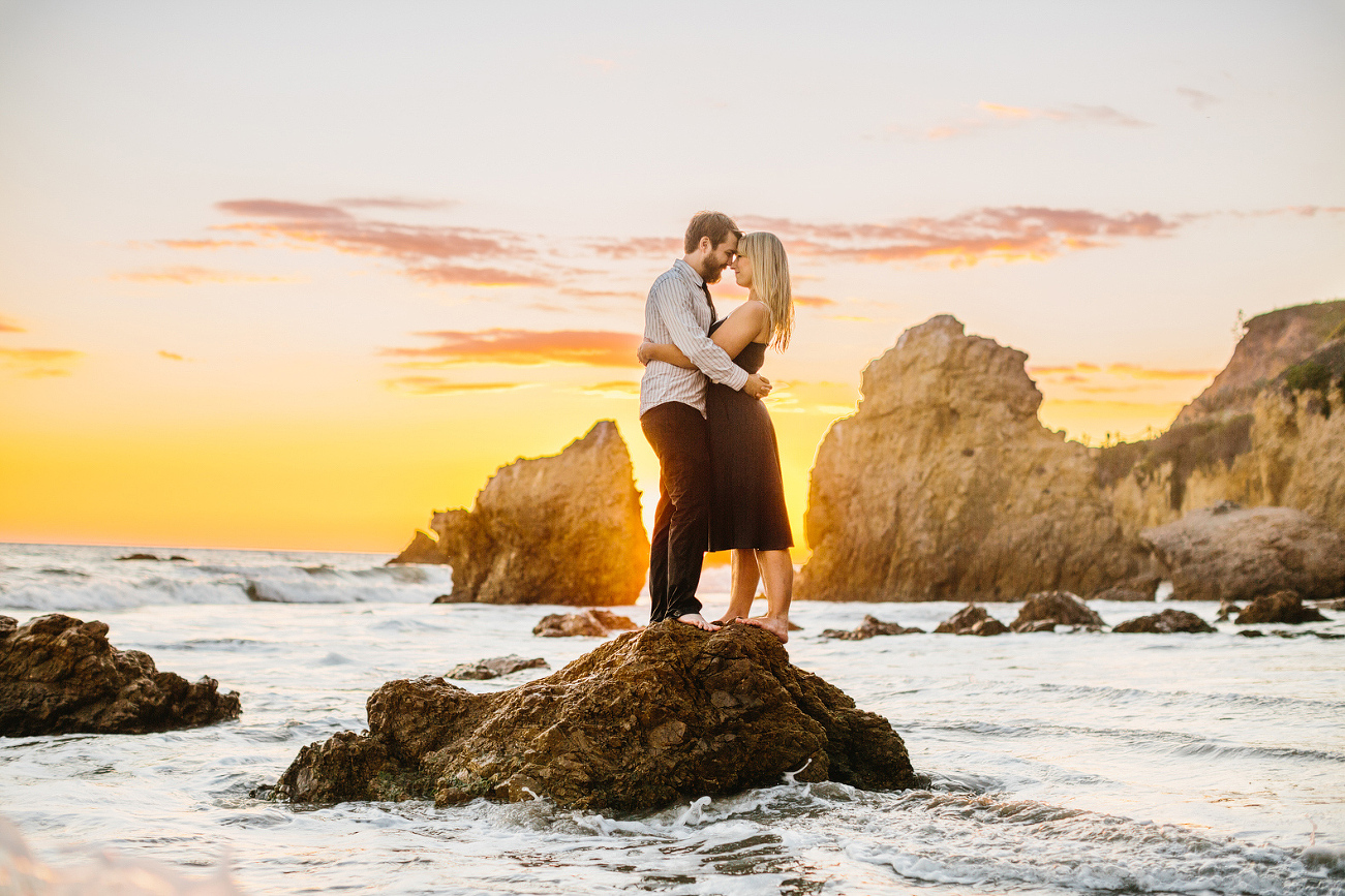 The couple on a rock surrounded by water. 