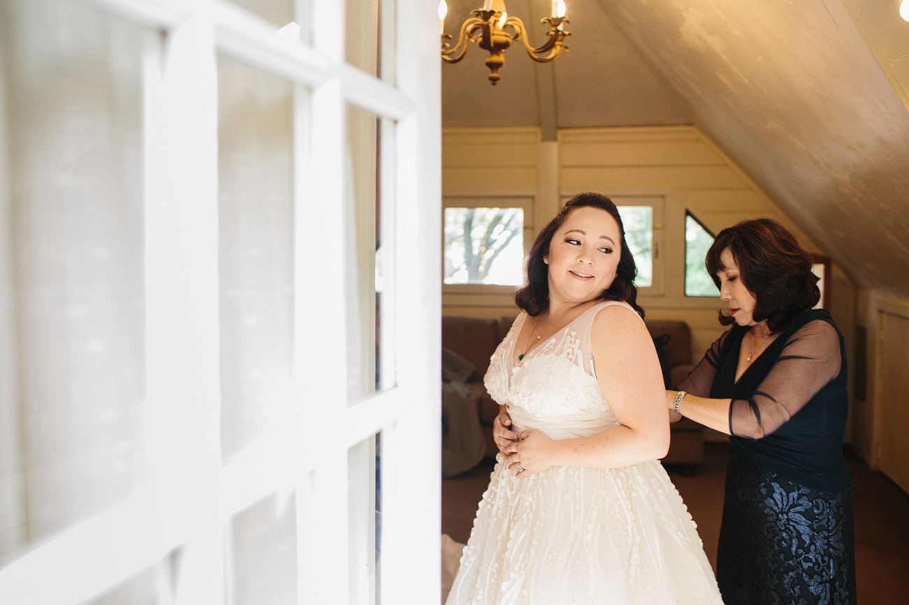 The mother of the bride helping her get dressed. 