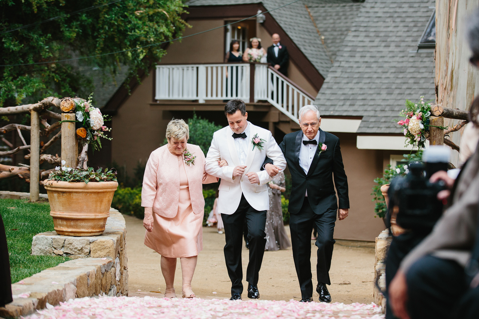 The groom walking down the aisle with his parents. 