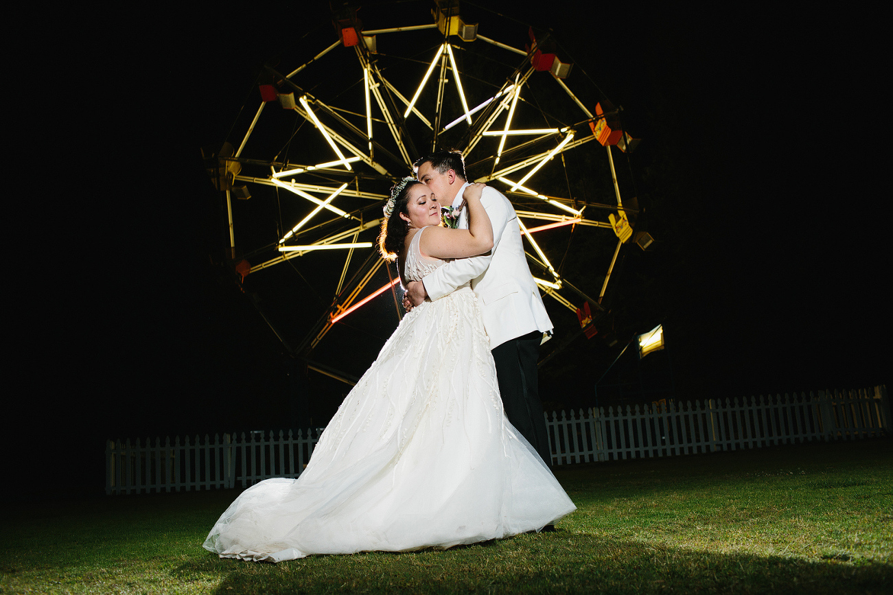 The couple in front of the ferris wheel at night. 