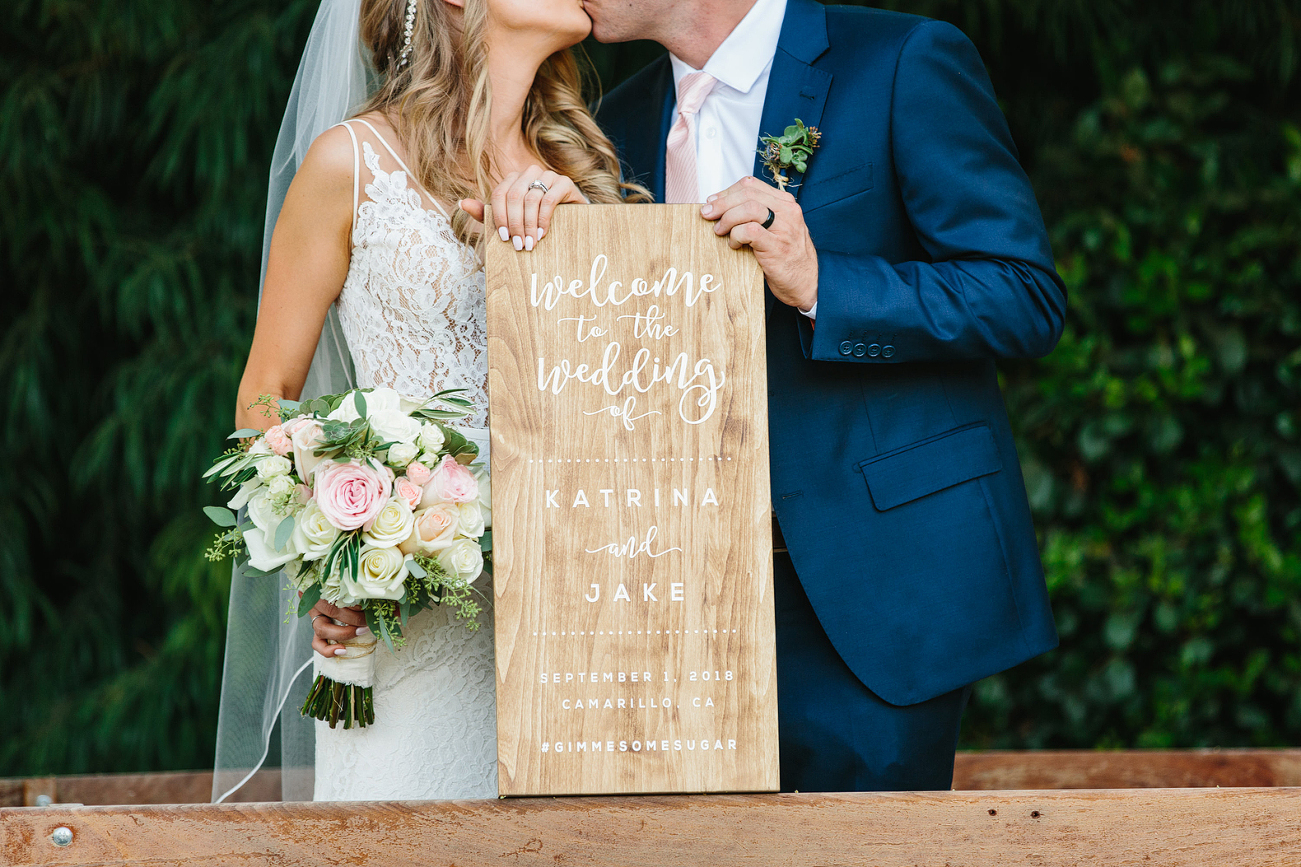 Bride and groom with their wooden wedding sign