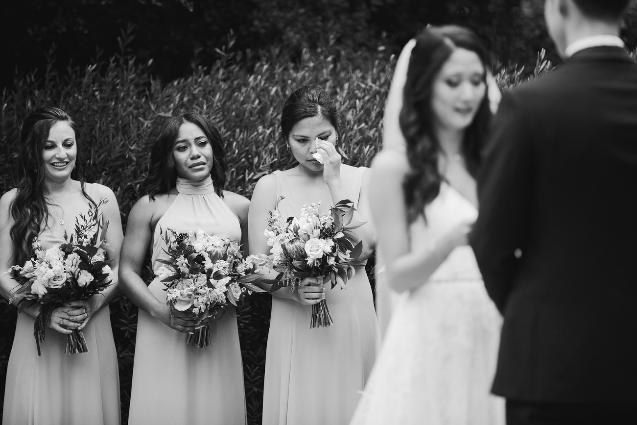 bridesmaids tearing up and crying in background at ceremony