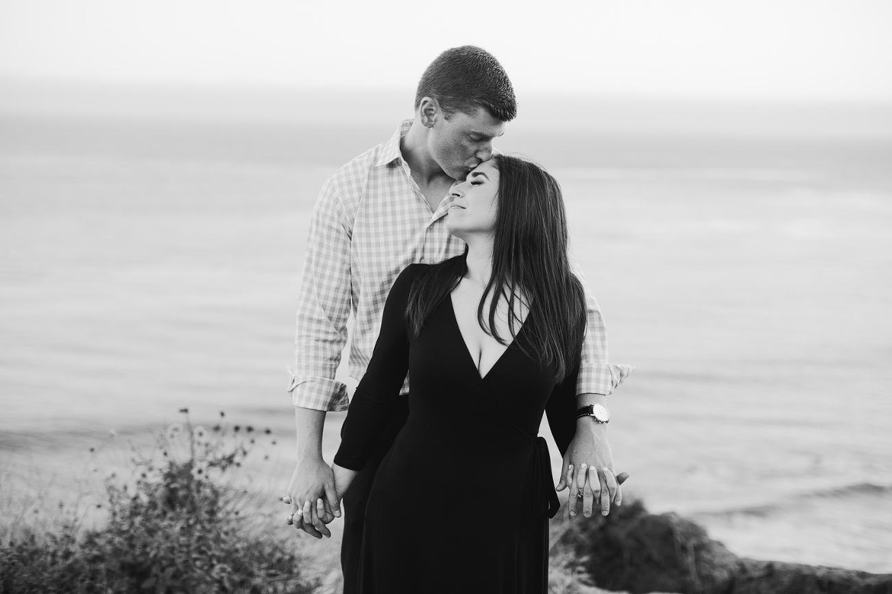 bride and groom at beach him kissing her forehead. black and white photo