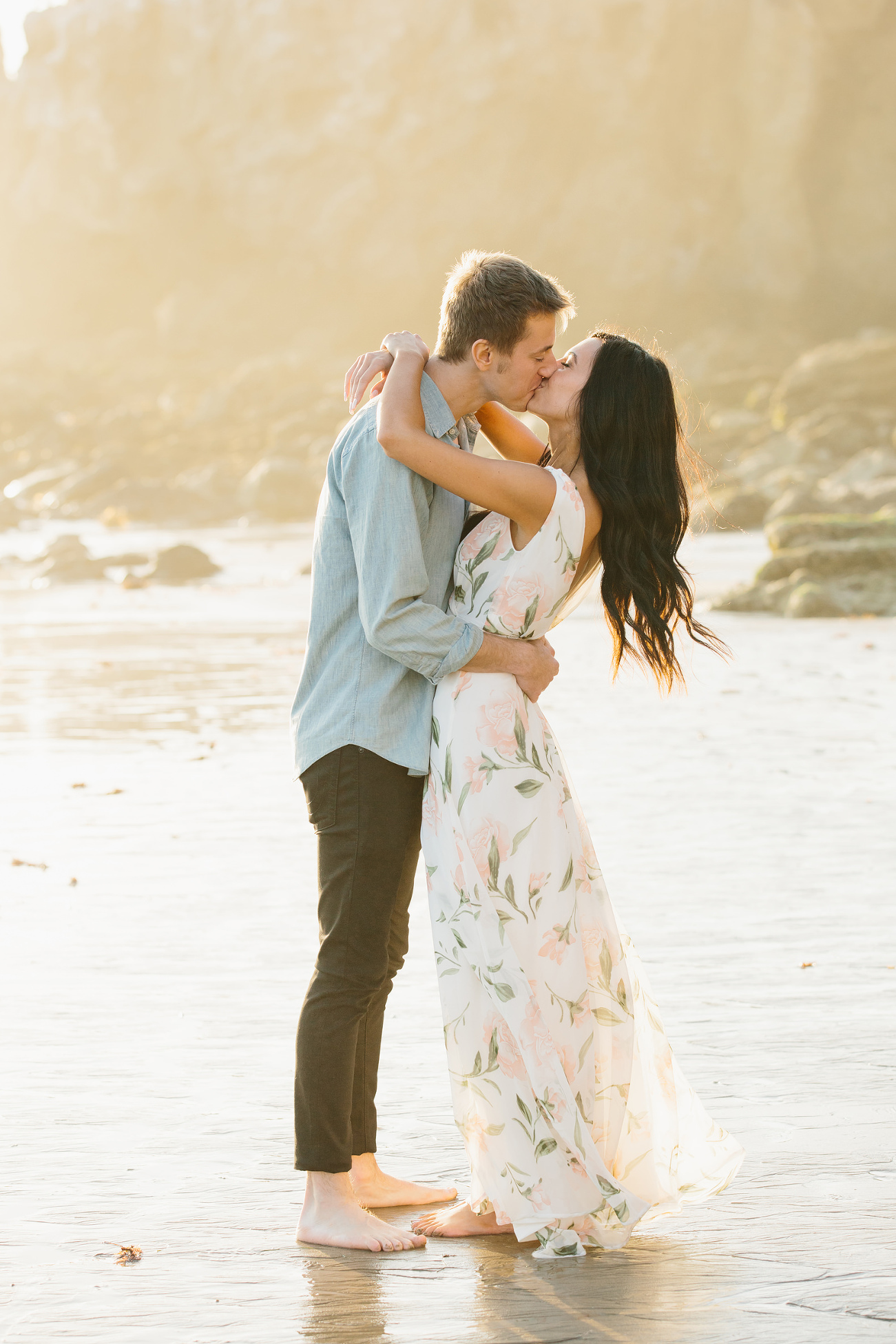 A girl and guy kissing on the beach in warm light