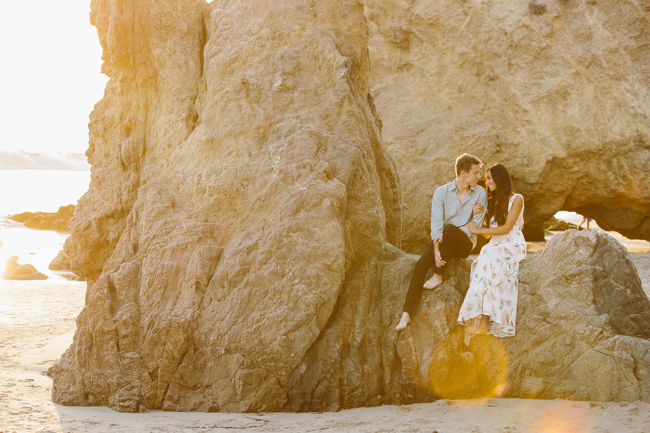 A couple who is getting married sitting on rocks at the beach in Malibu California