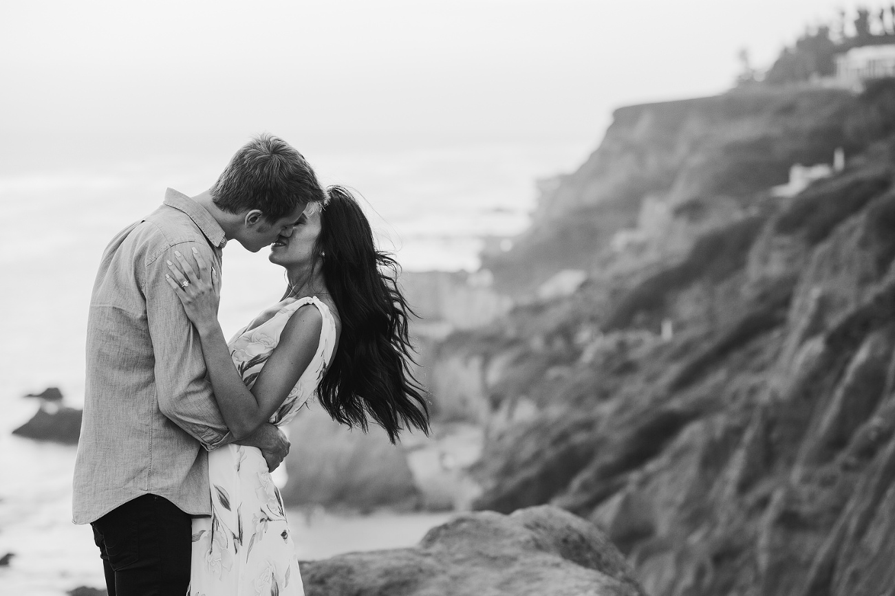 black and white engagement photo with the wind blowing in the brides hair
